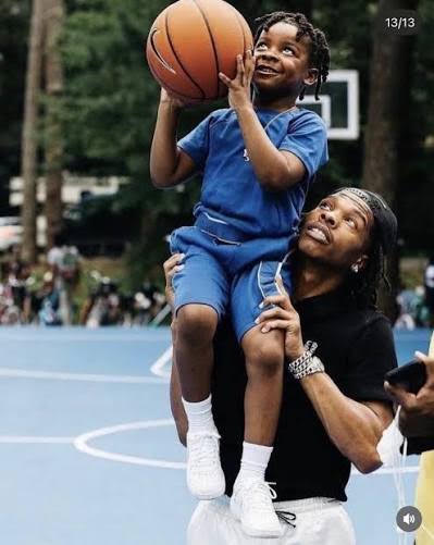 A child holding a basketball while seated on an adult's shoulders